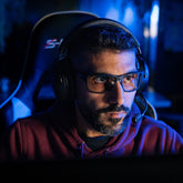 Gamer with a headset wearing ARC 74 gaming glasses in front of a screen  