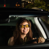 Smiling woman driving at night wearing Lucent night driving glasses